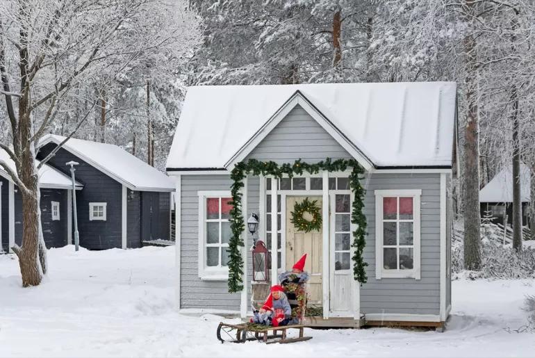 Small grey cottage decorated with garlands and a wreath