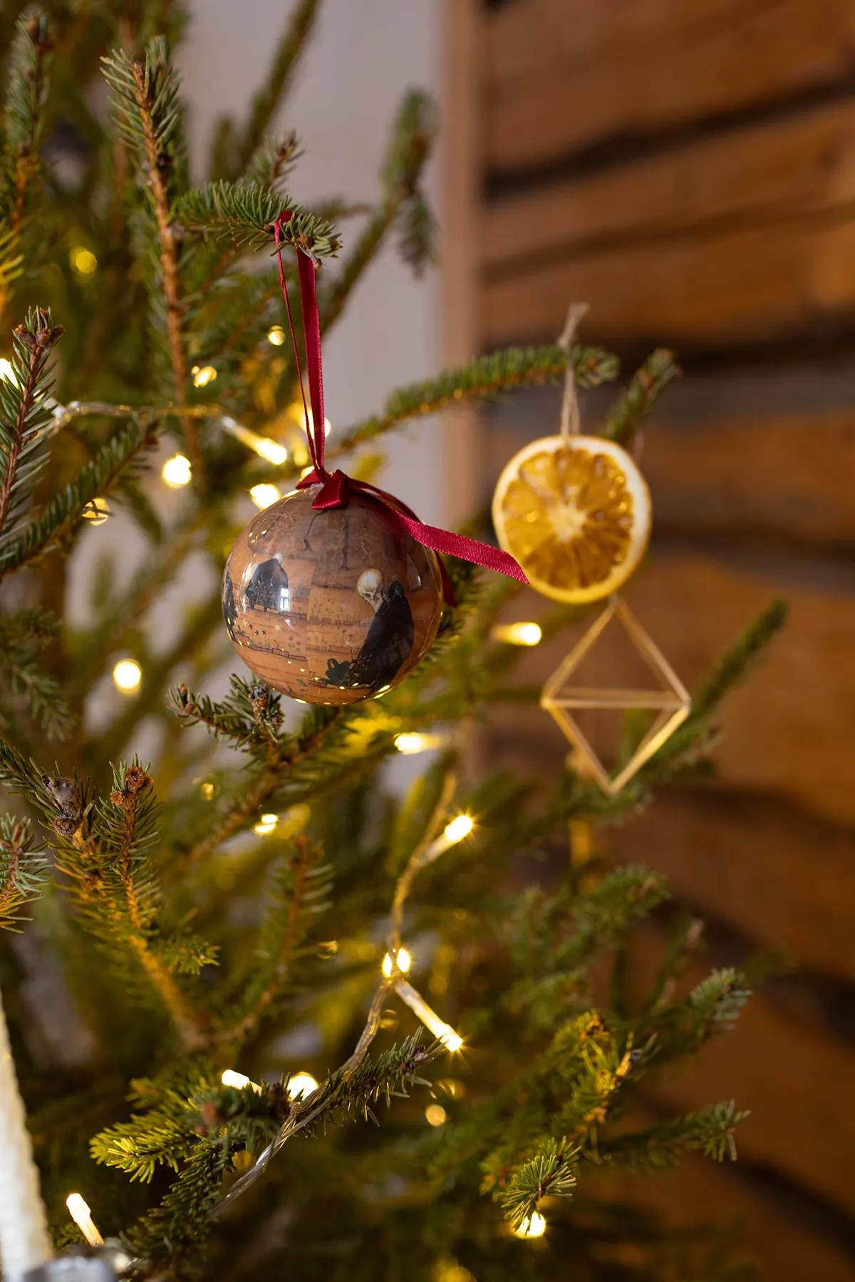 Close-up of Christmas ornaments: a garland, a bauble with a red ribbon, a dried orange and a gold geometric ornament