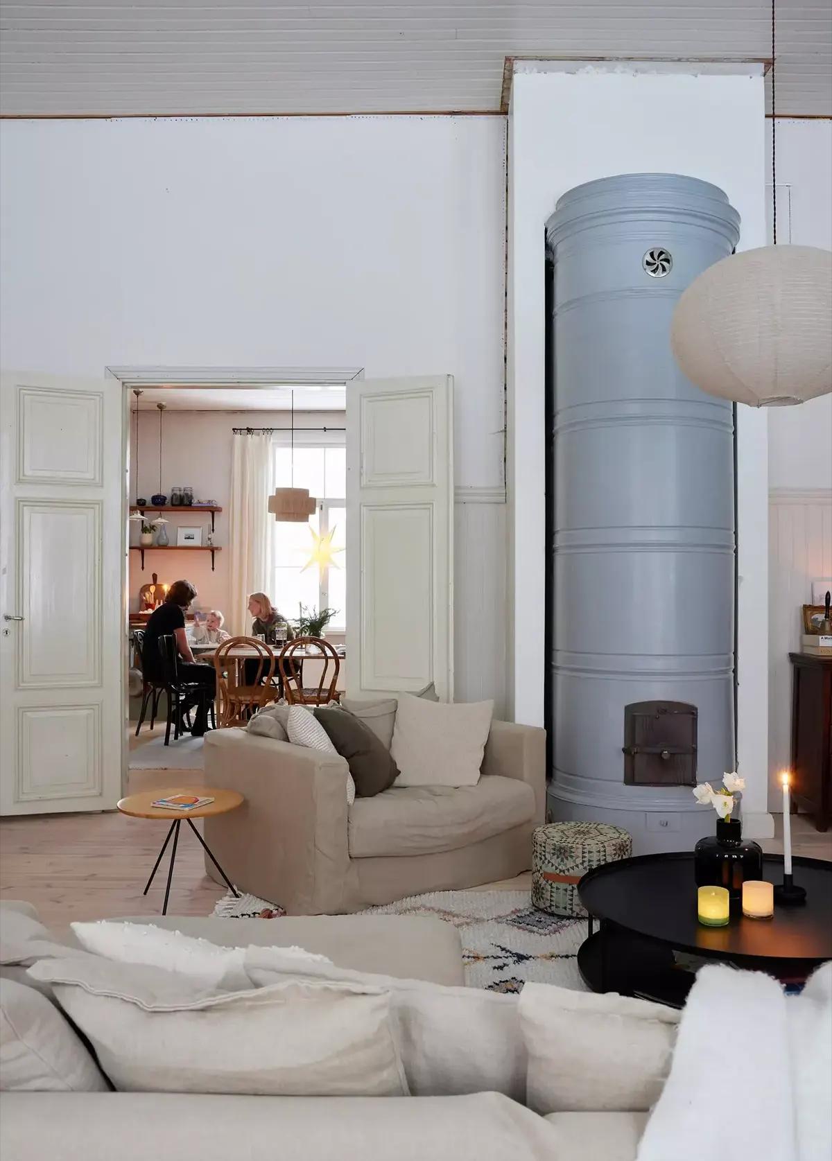 Living room with a beige sofa, tall grey stove and a view of the dining area