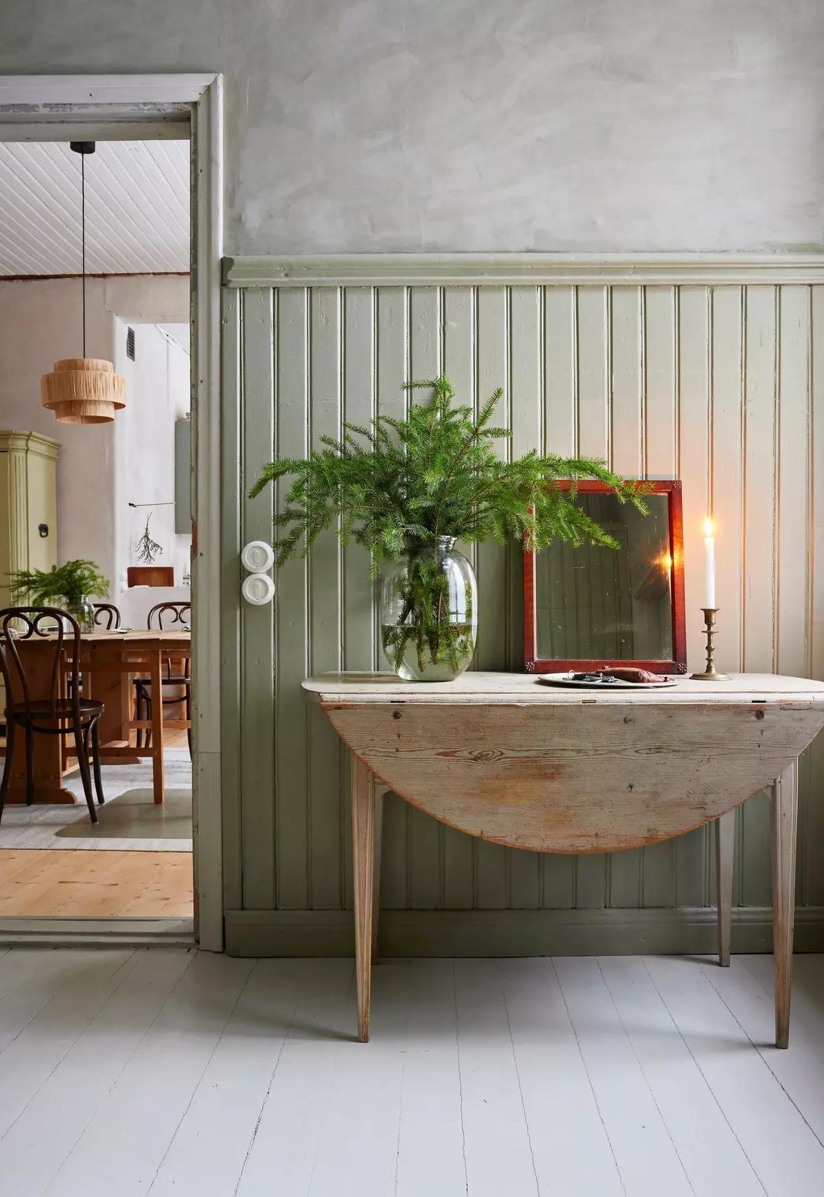 Console table styled with fir branches in a vase, a mirror and a candle