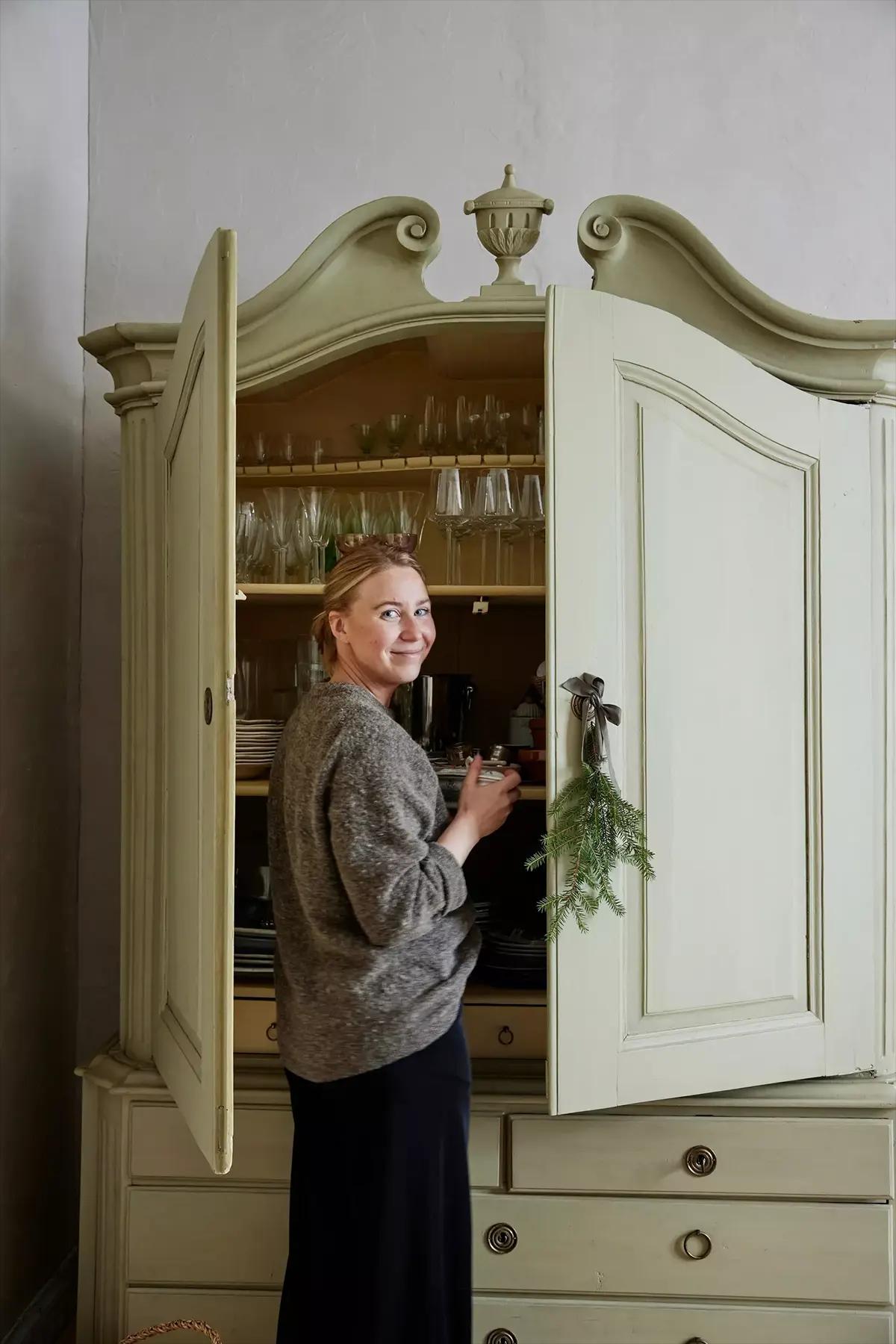 Woman standing next to an open light-green cabinet