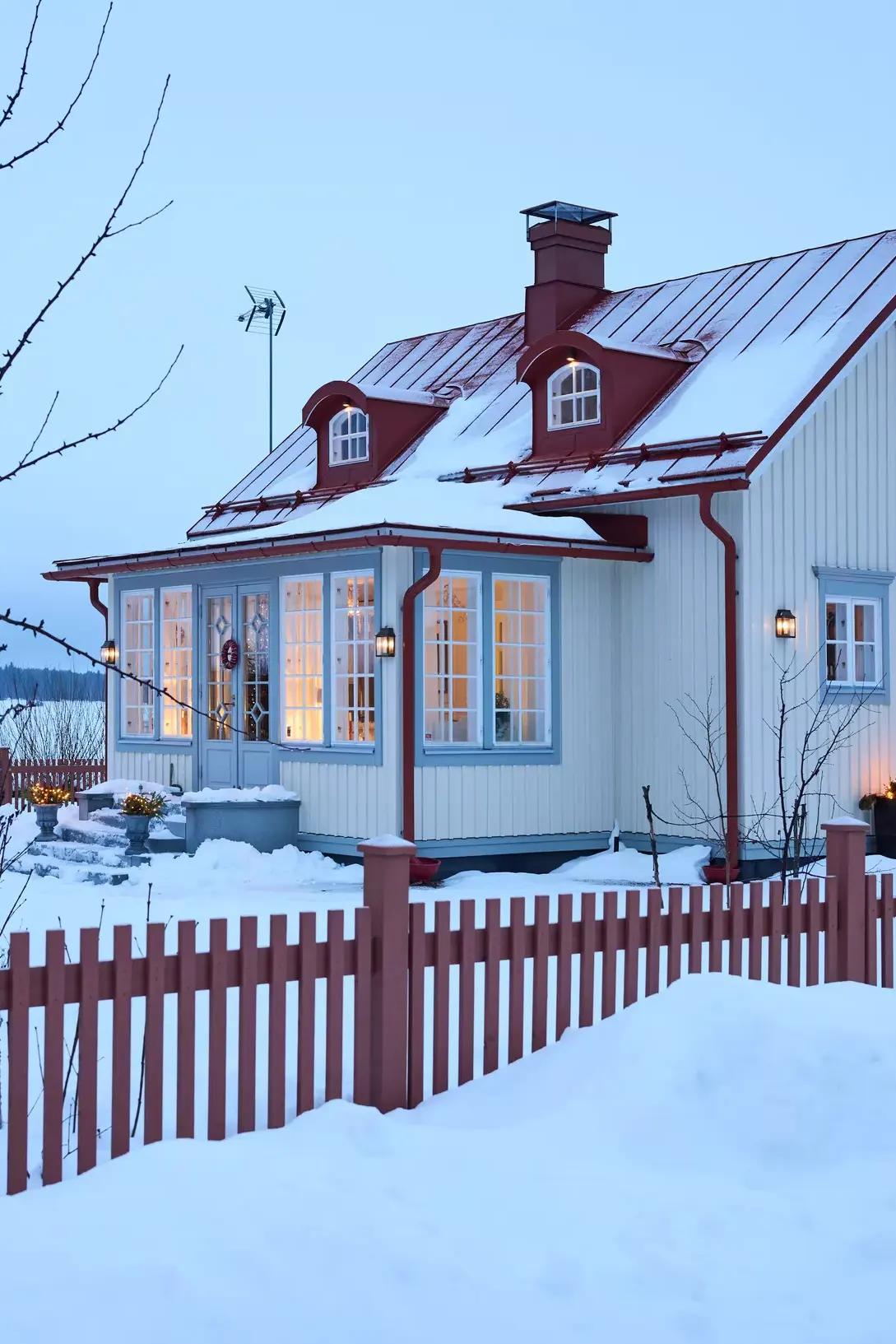 Finnish house with a red, snow-covered roof and a fence