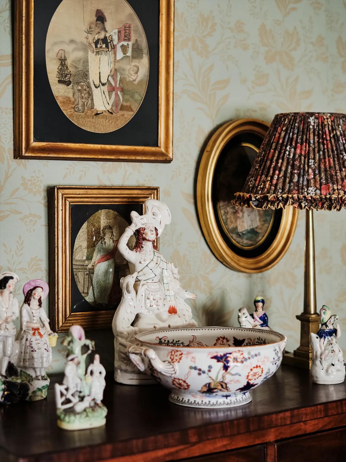 Dresser topped with decorative dishes, figurines, lamp and framed pictures