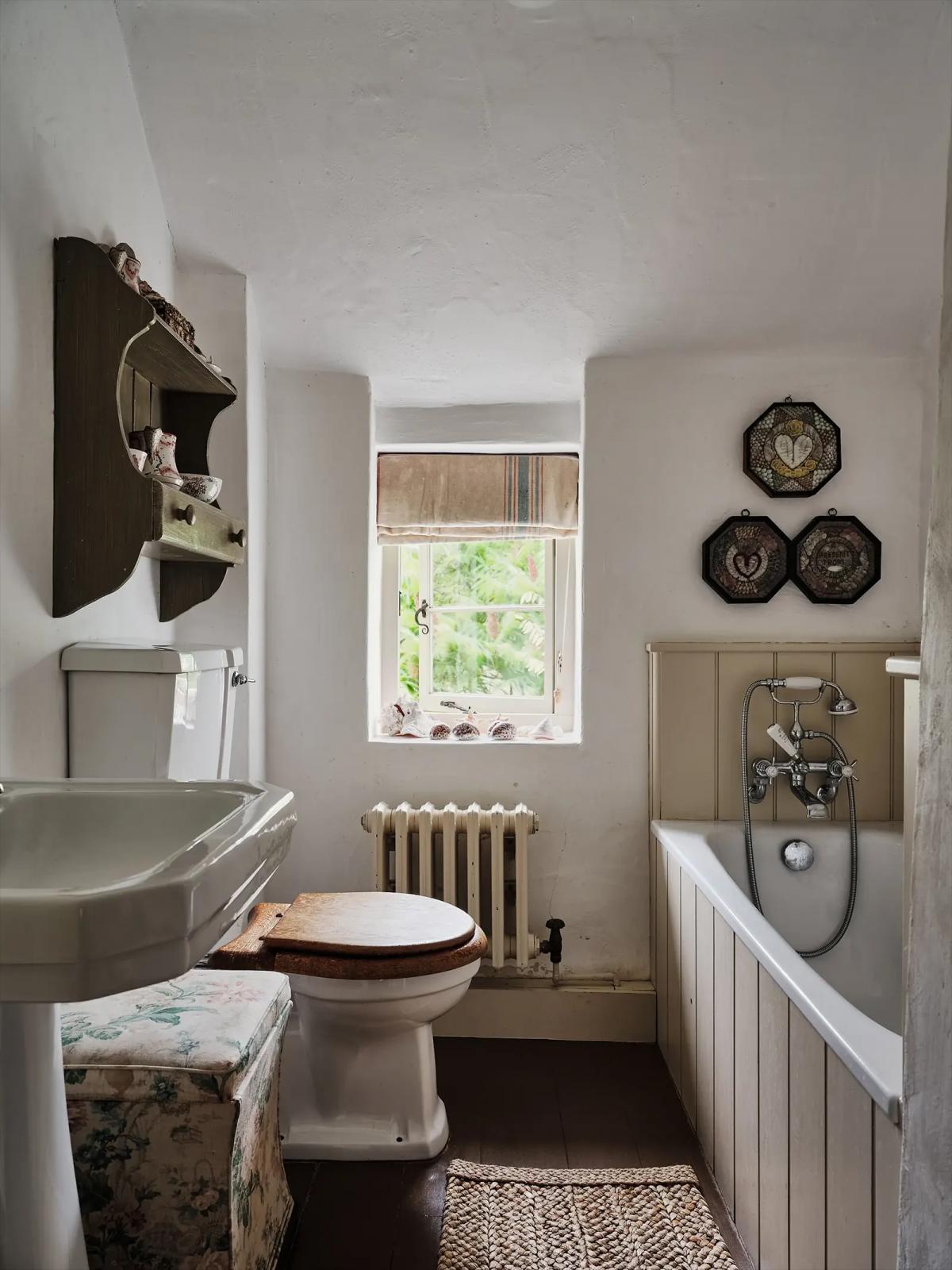Bathroom in the old cottage with bathtub, toilet, sink and shelving