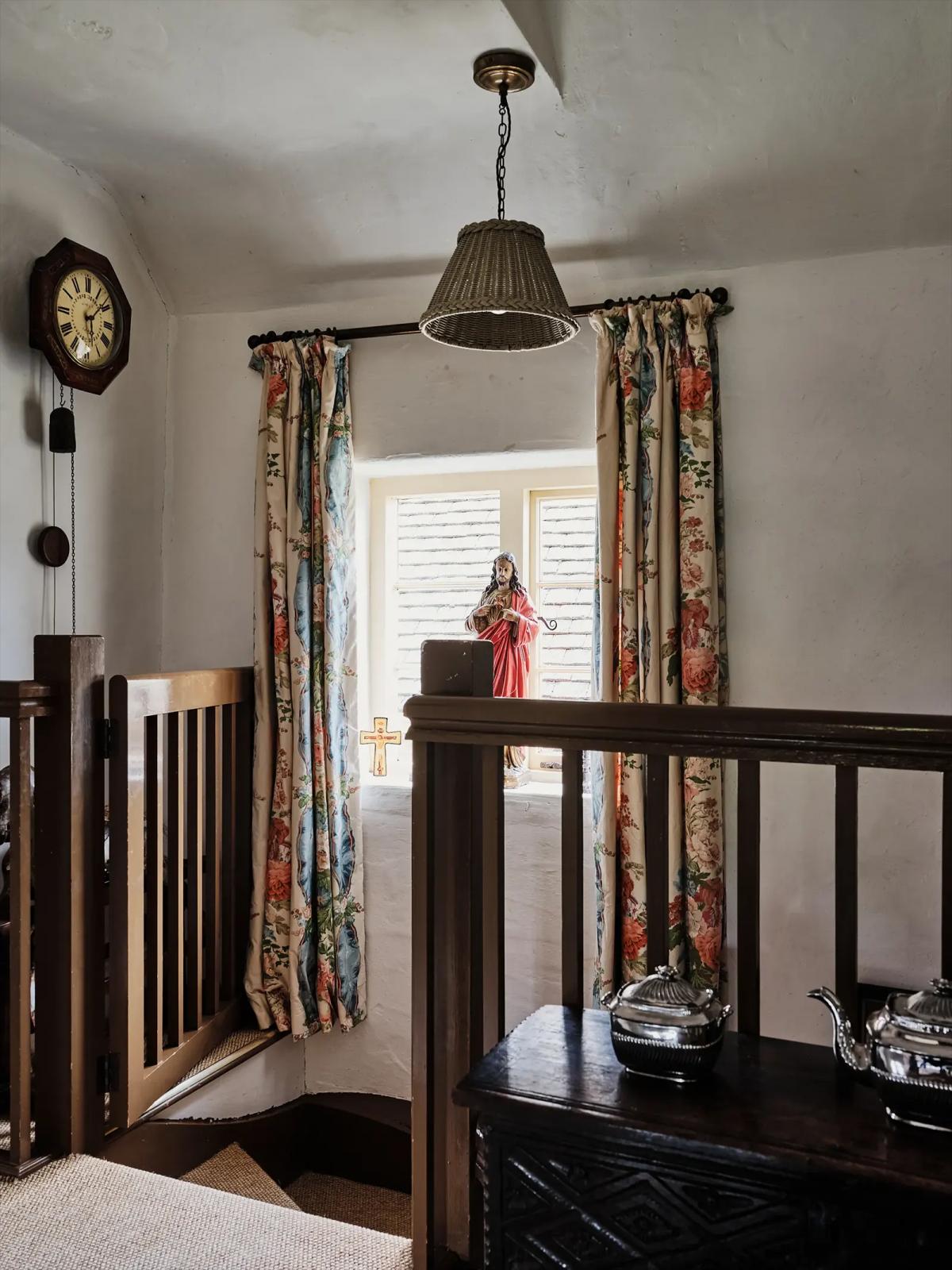 Staircase with a clock, lamp, colorful curtains and a statue on the sill