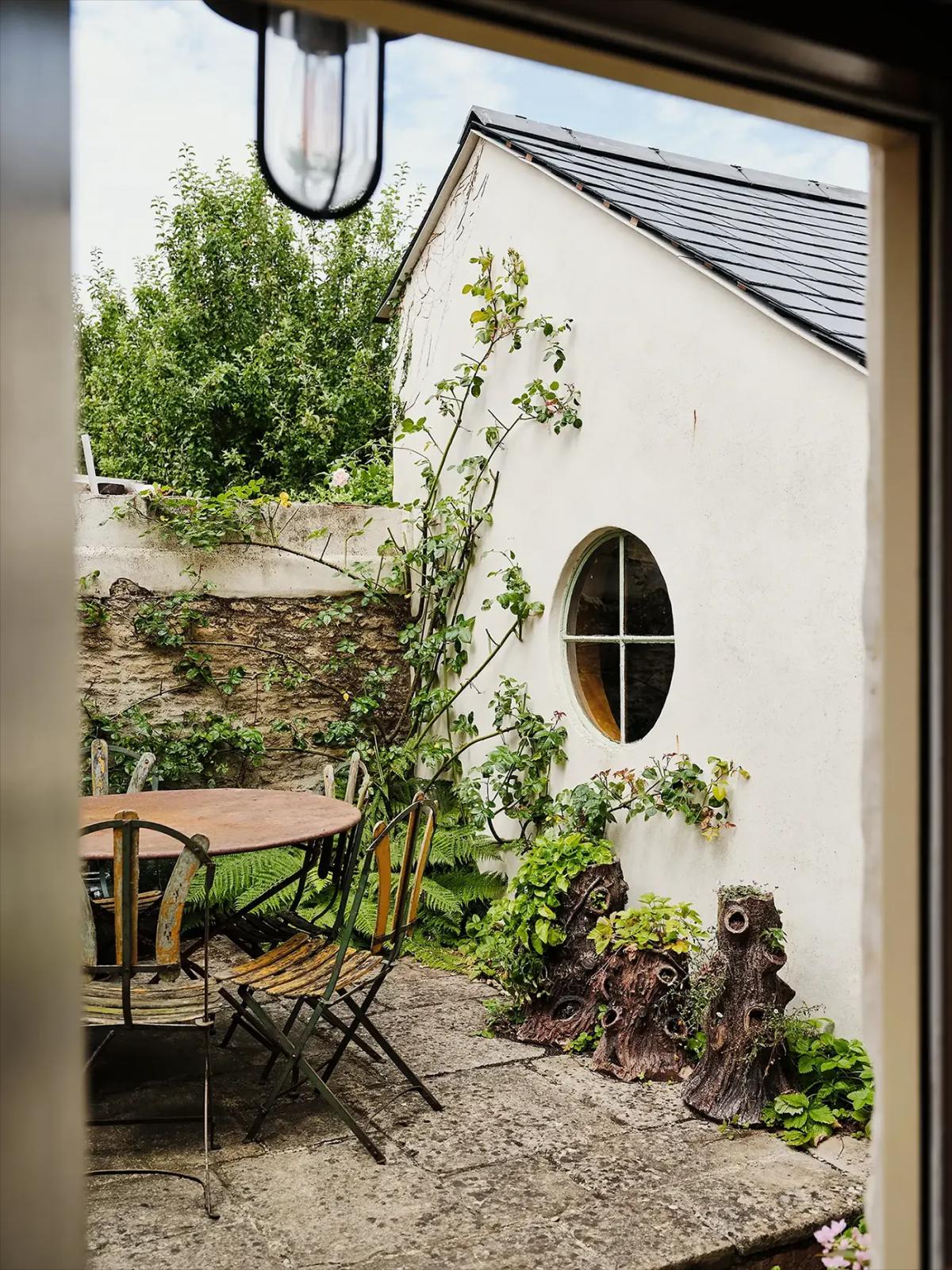 Courtyard view with metal table, chairs and climbing plants