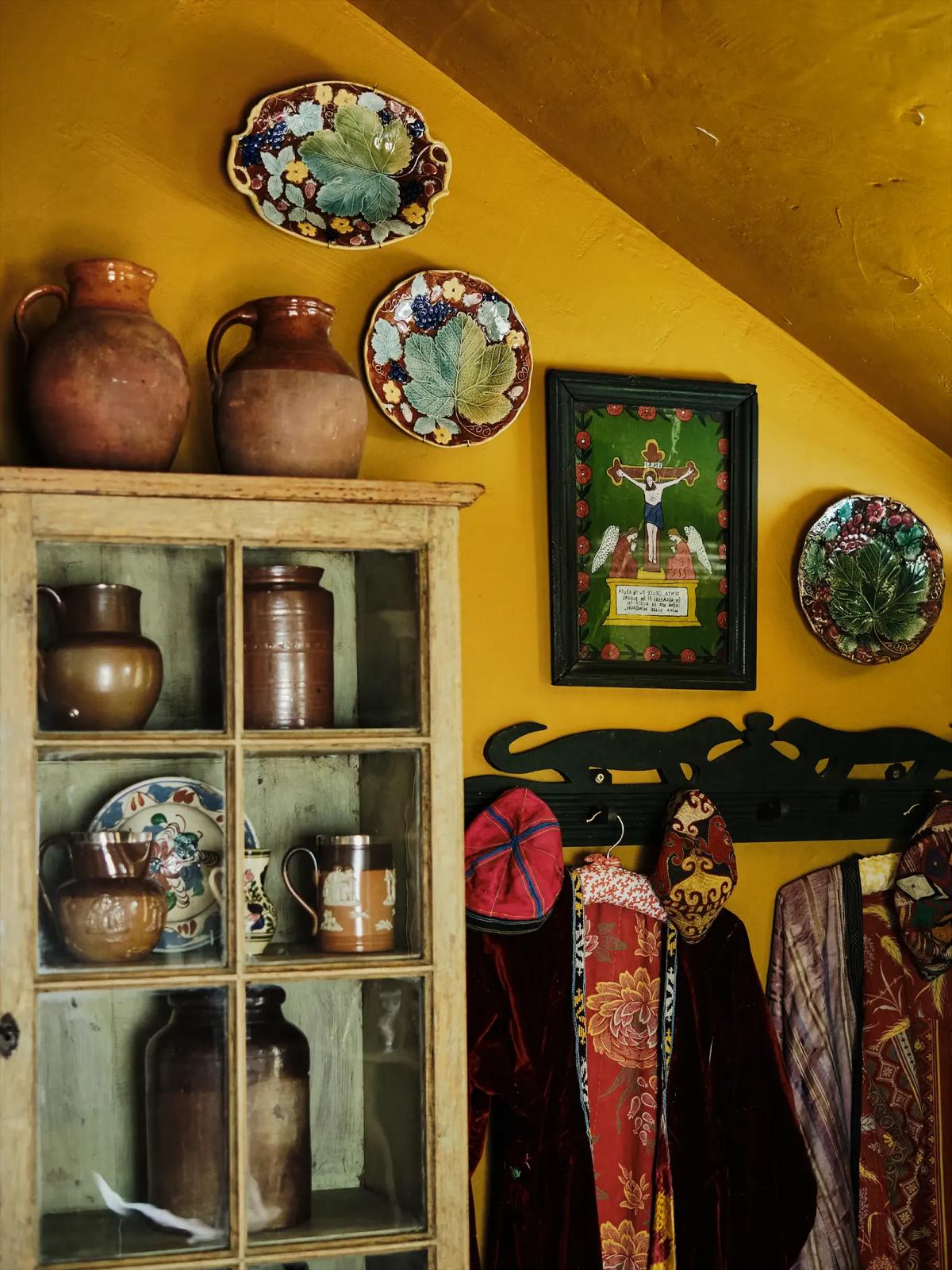 Yellow wall with an old dish cabinet, coat rack and decorative plates