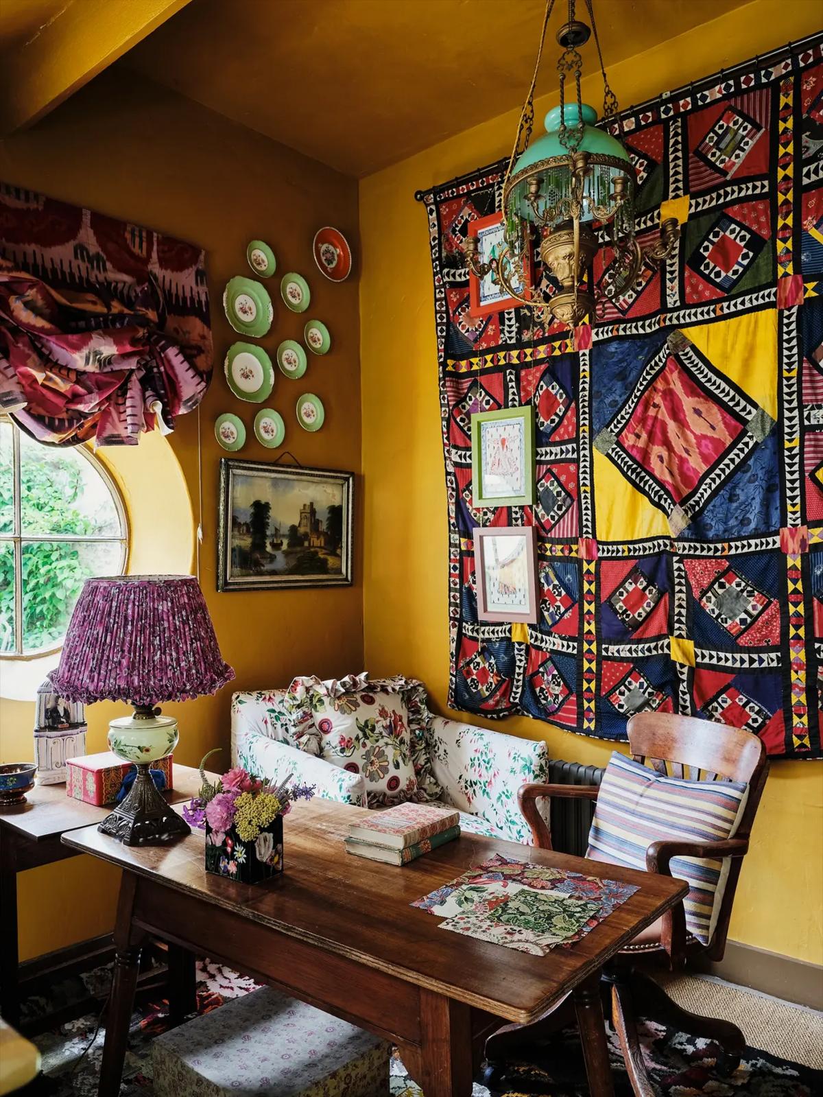 Cozy corner with yellow walls, armchair, side table, lamp and tapestry