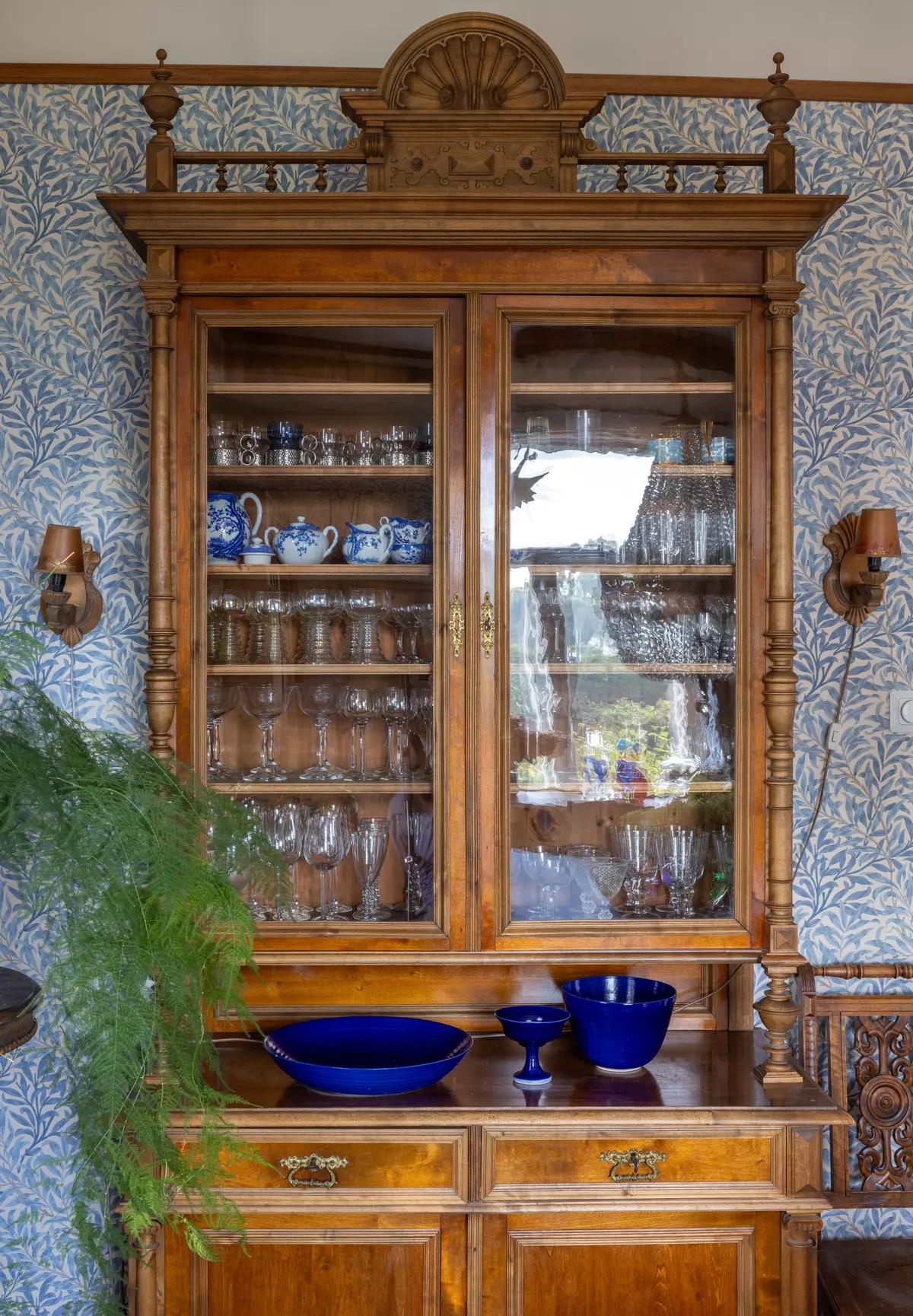 Old wooden display cabinet with glass doors and dishes inside