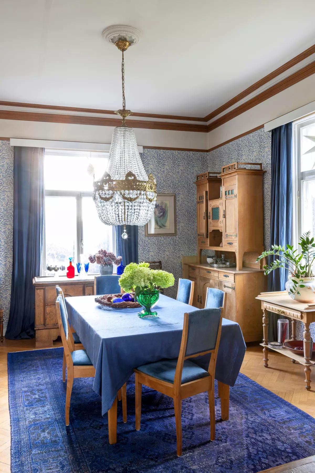 Dining area with wooden chairs, a blue tablecloth and a rug under the table
